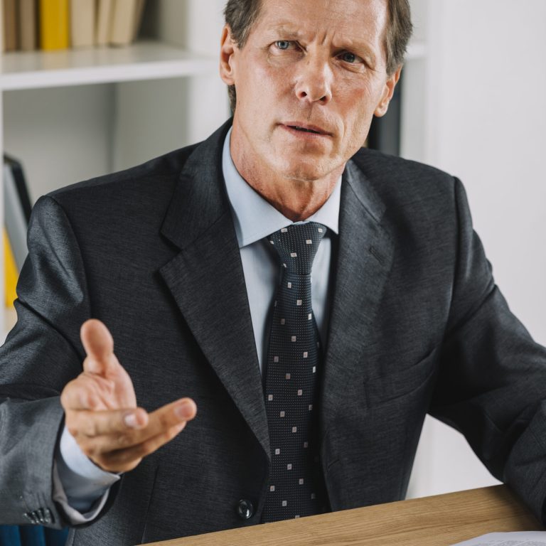 portrait-mature-businessman-workplace-gesturing